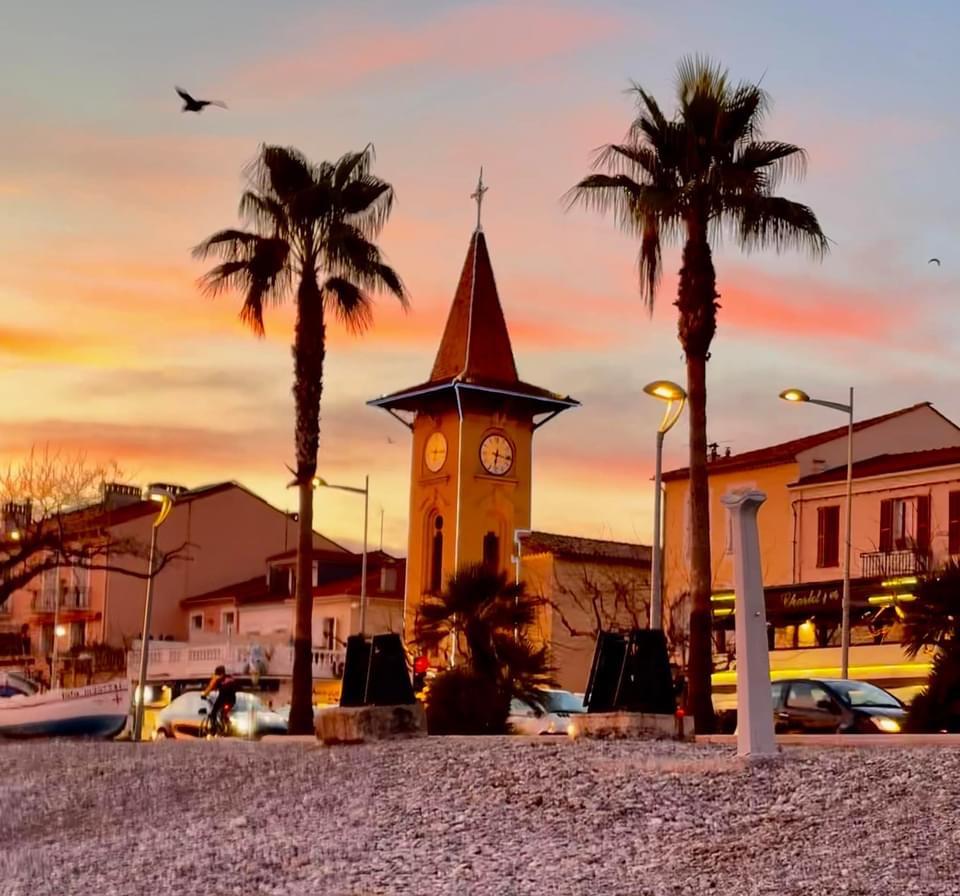 A clock tower with palm trees and buildings

Description automatically generated