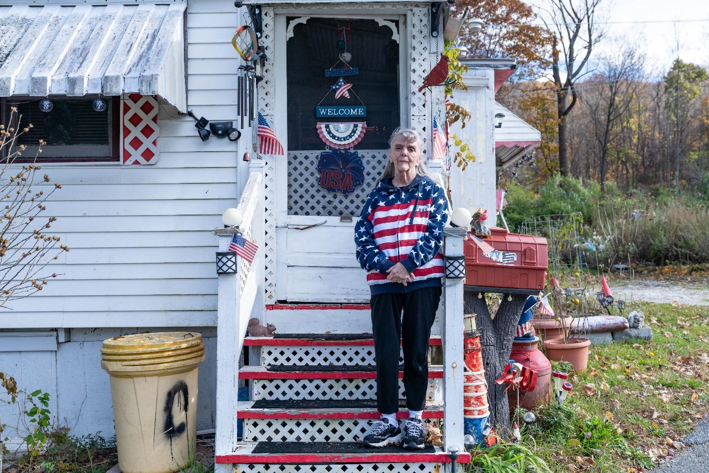 A person standing on a porch of a house

Description automatically generated