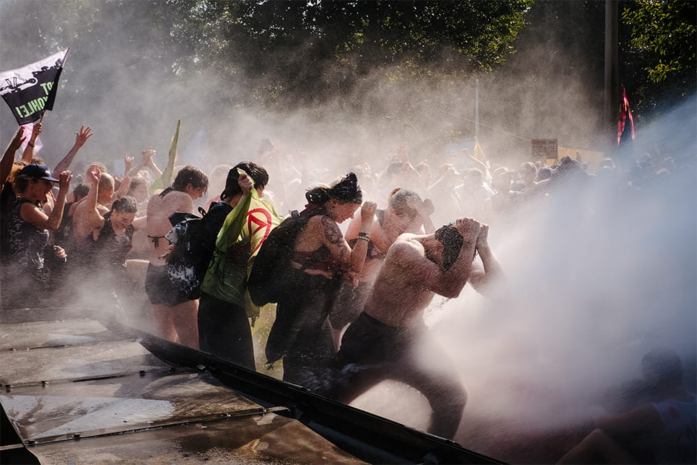 Rebels brace themselves as a powerful water cannon is fired at them