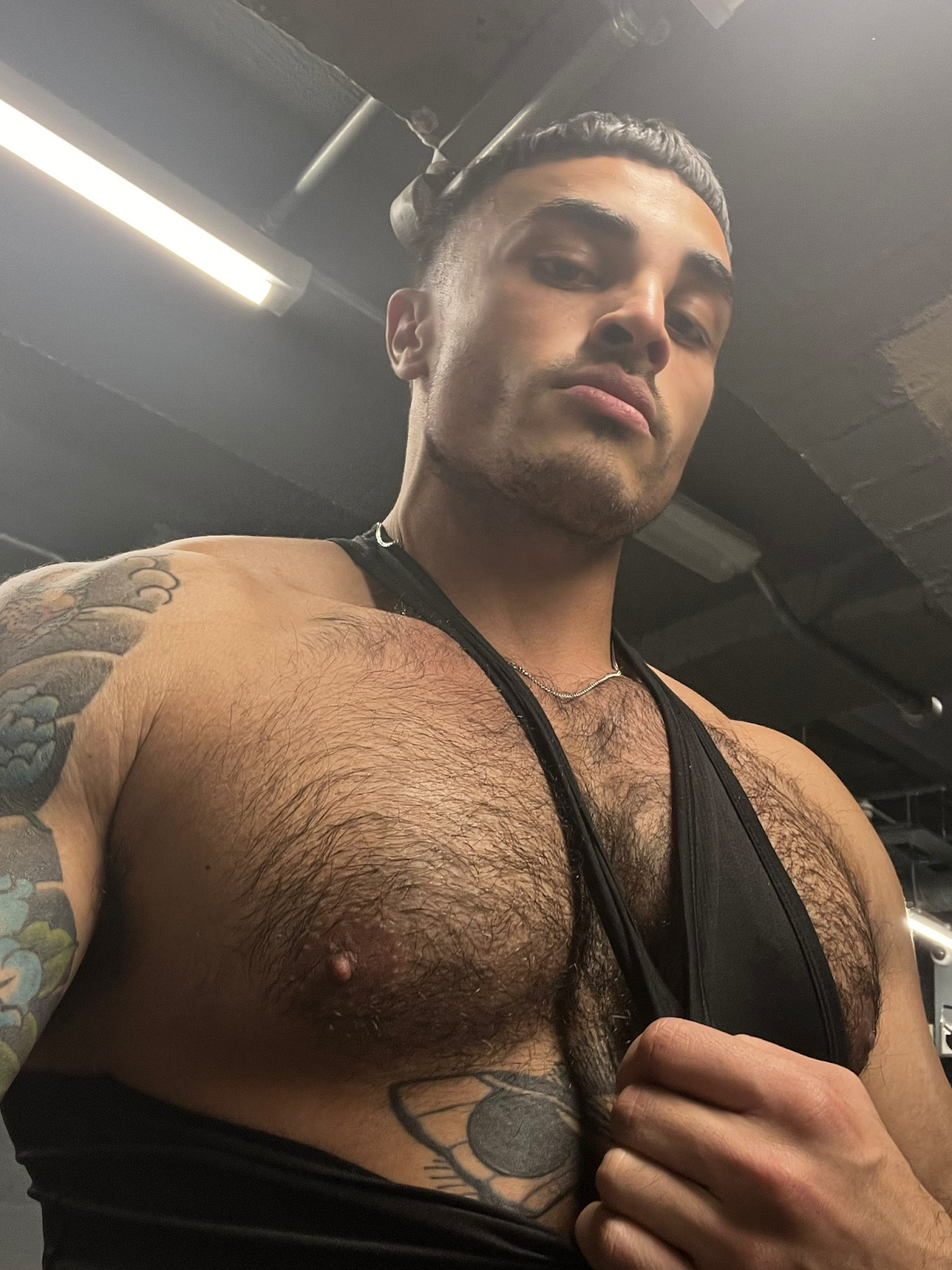 Nick_at_Night at the gym pulling down his black tank top to reveal his gay hairy nipples and chest tattoos