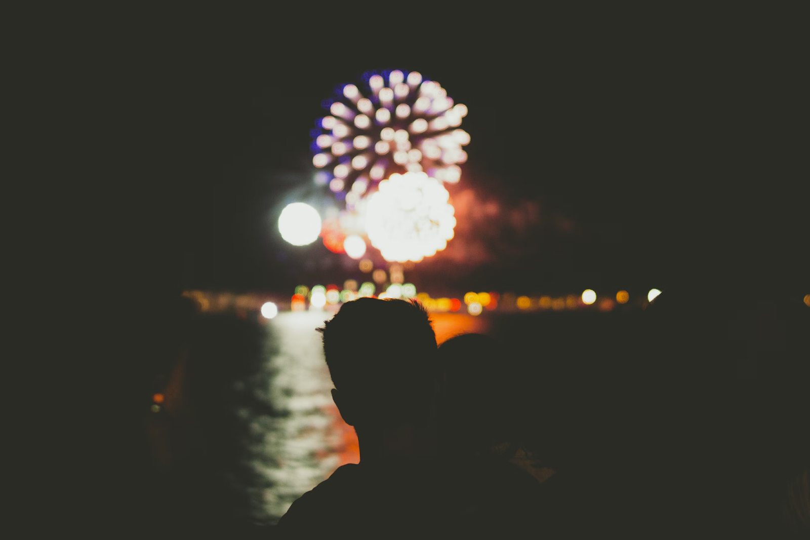 The silhouette of a man watching New Year's fireworks from a distance.