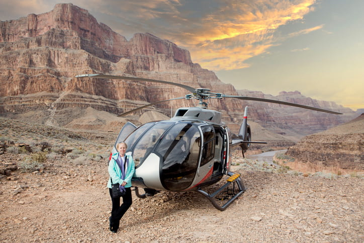 A tourist explores the north rim of the Grand Canyon with the assistance of a helicopter flight. Here she is posing with the helicopter.