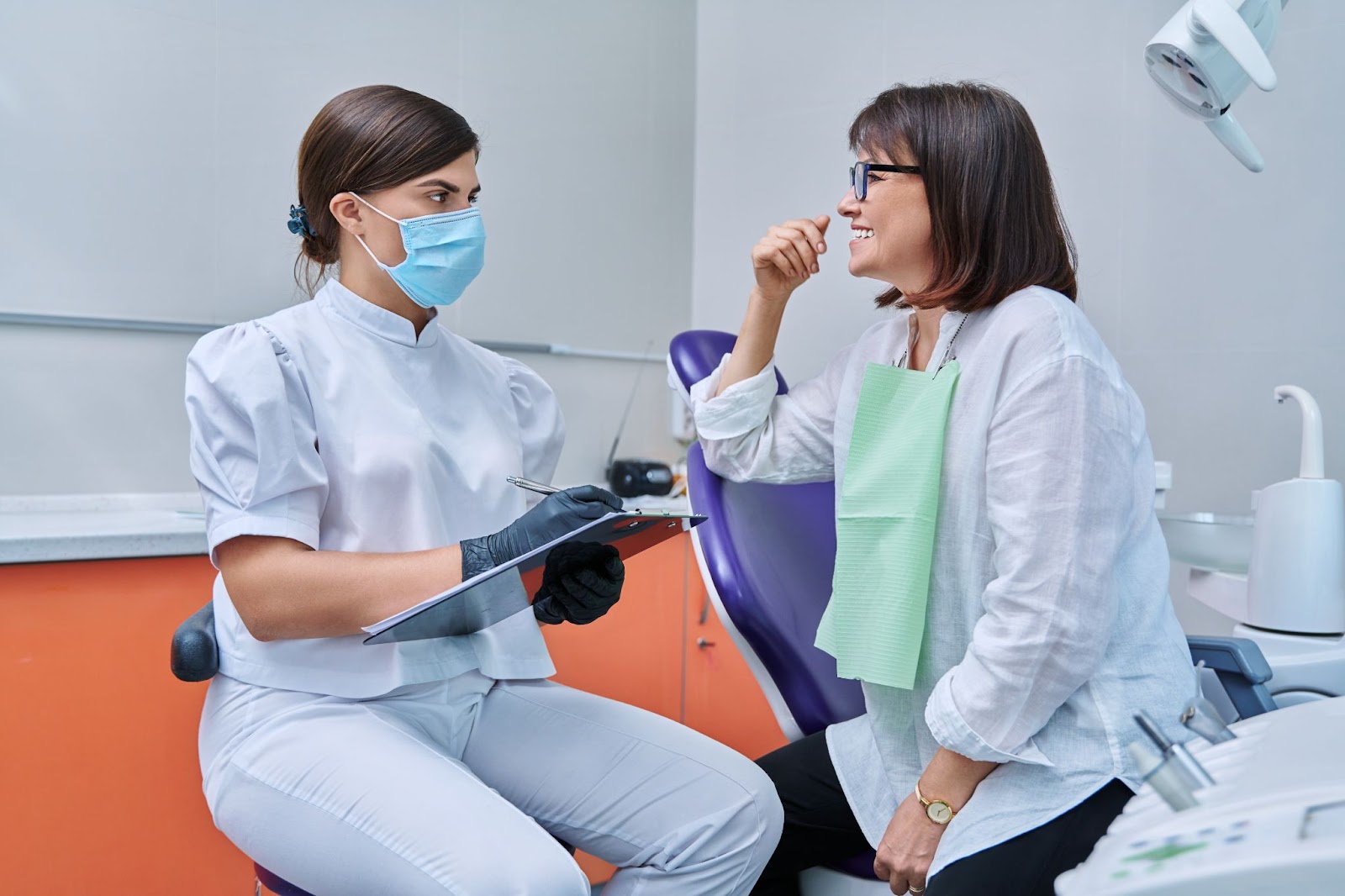 Patient talking to dentist smiling dentist taking down notes 