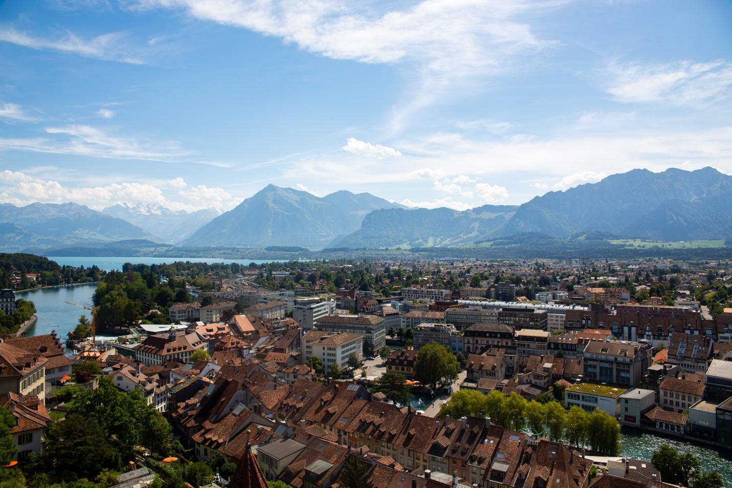 A city with many buildings and trees and mountains in the background

Description automatically generated