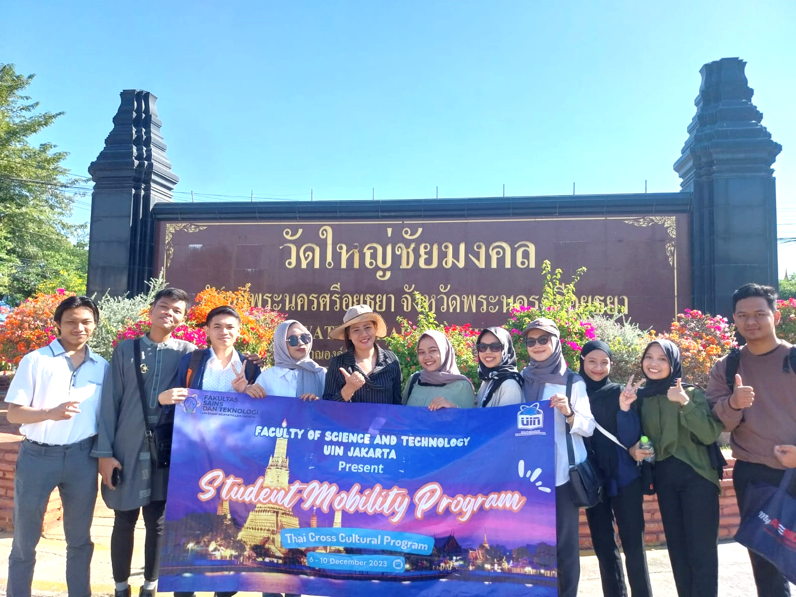 A group of people posing for a photo in front of a sign

Description automatically generated