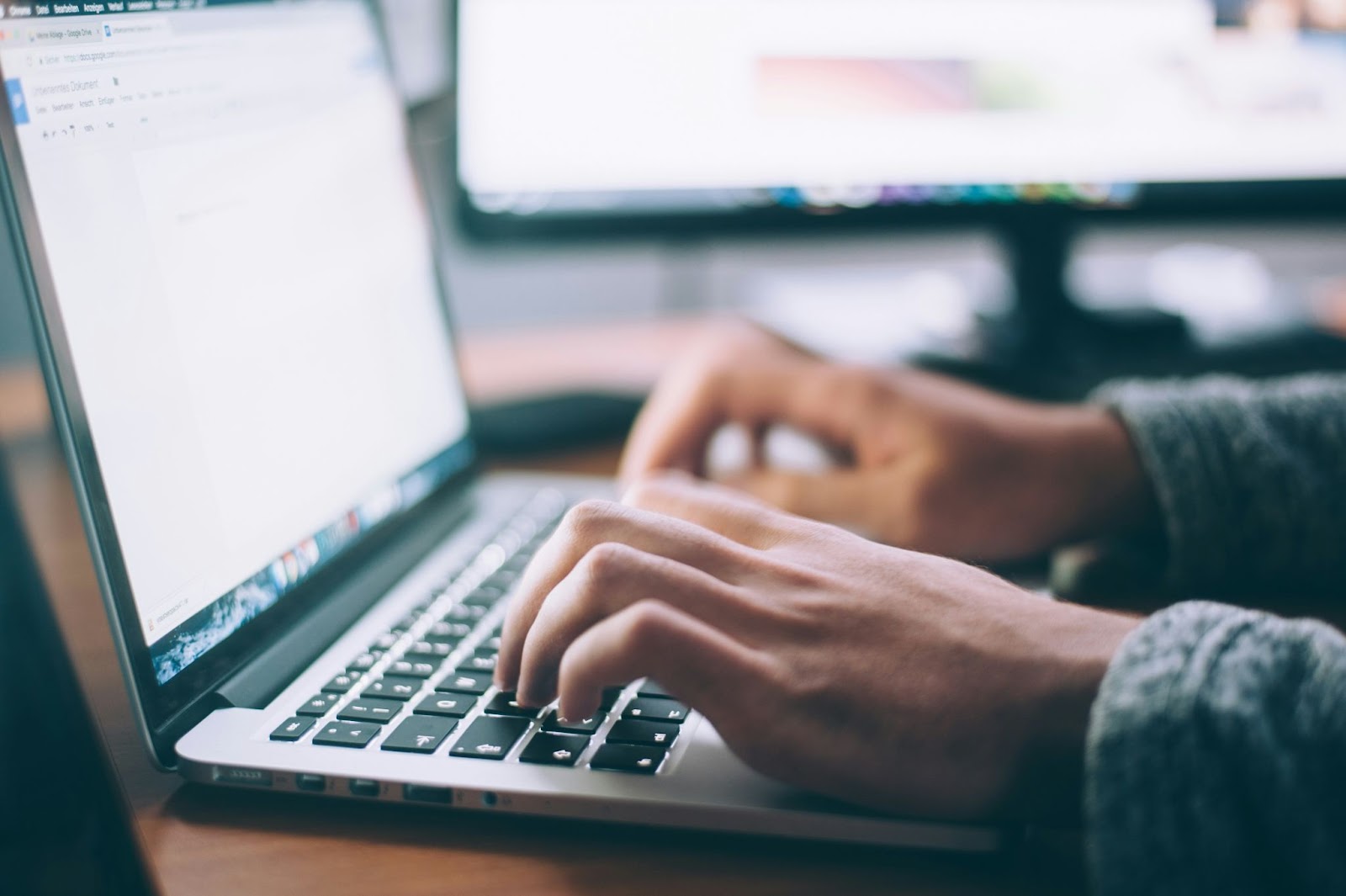 Manos escribiendo contenido SEO en una laptop sobre mesa de madera