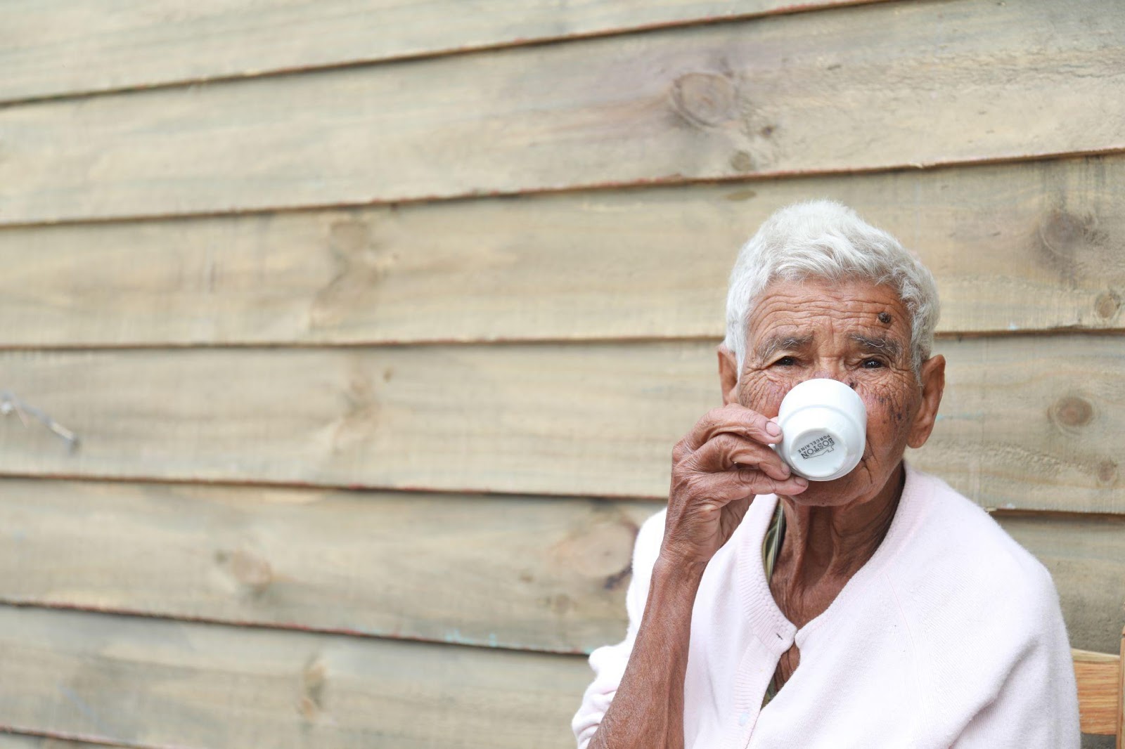 An older man sitting drinking a cup of coffee or tea, as part of a conversation on dehydration in seniors