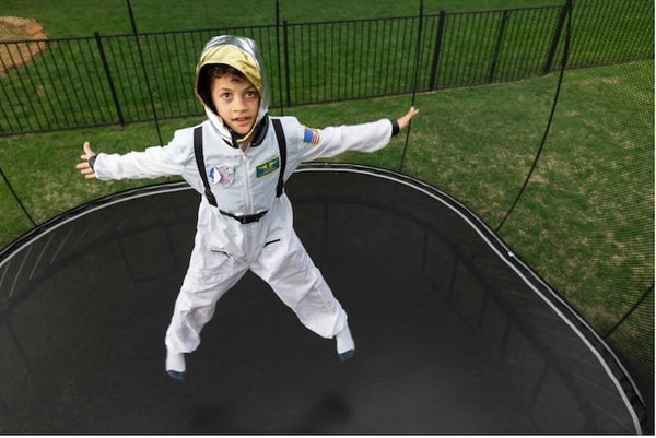 A child dressed as an astronaut jumping on a trampoline.