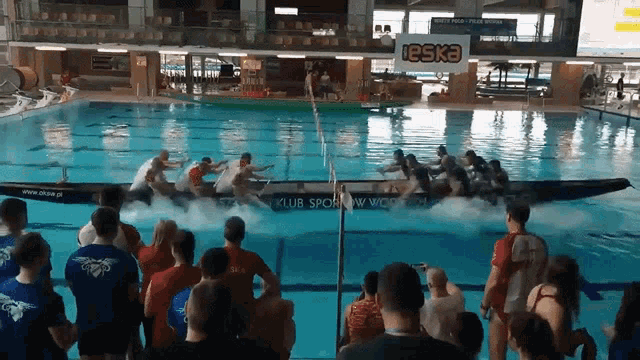 A group of people in a boat racing in a pool