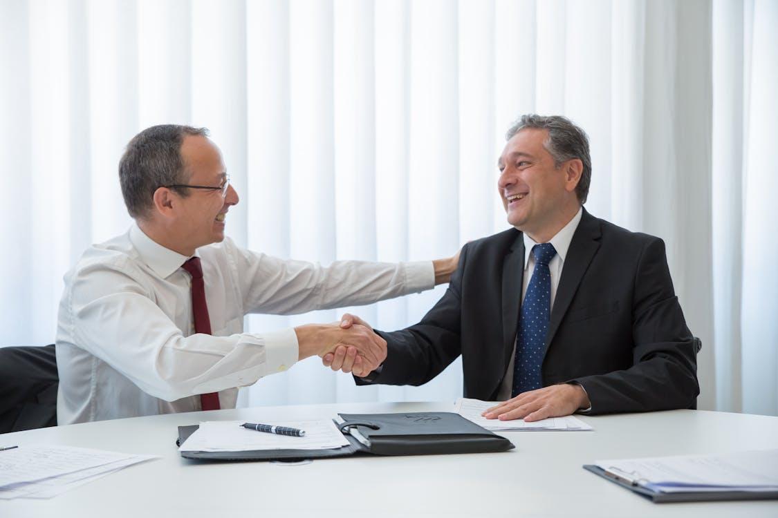 Free Men Looking at Each Other while Doing Hand Shake Stock Photo