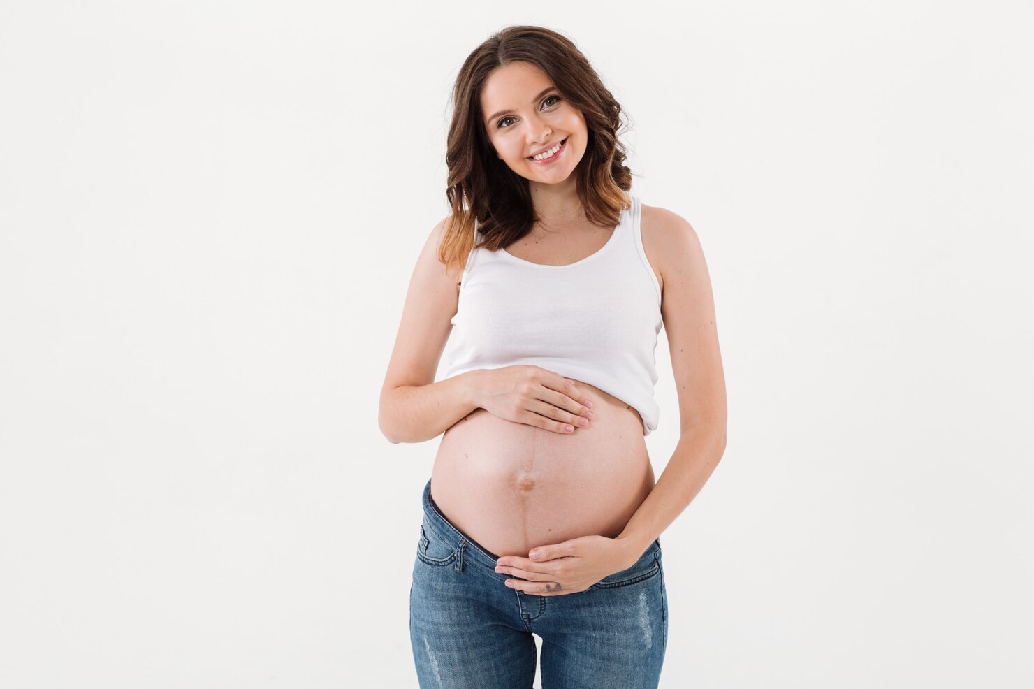 A joyful pregnant woman laughing while holding her belly.
