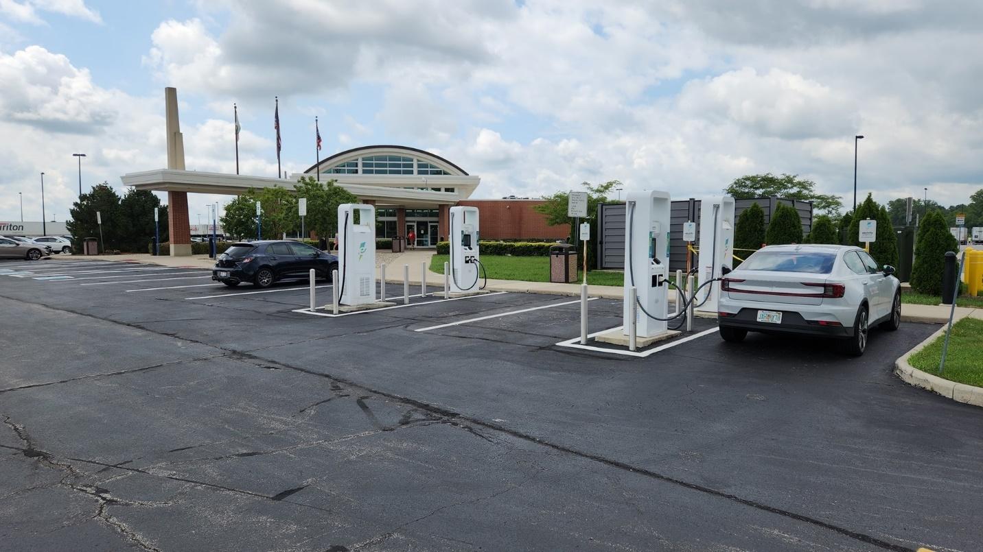 A car charging station with cars parked in the back

Description automatically generated with medium confidence