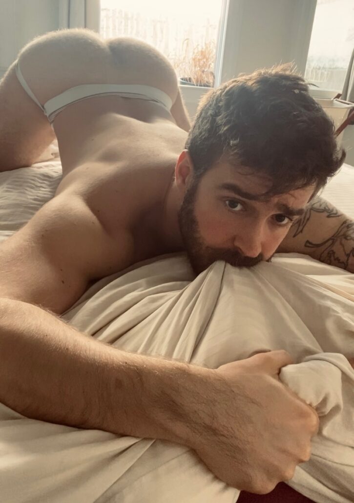 Forest Cliff biting down on the sheets naked wearing a white jockstrap with his gay bubble butt in the air