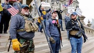 A group of people holding signs and holding guns

Description automatically generated