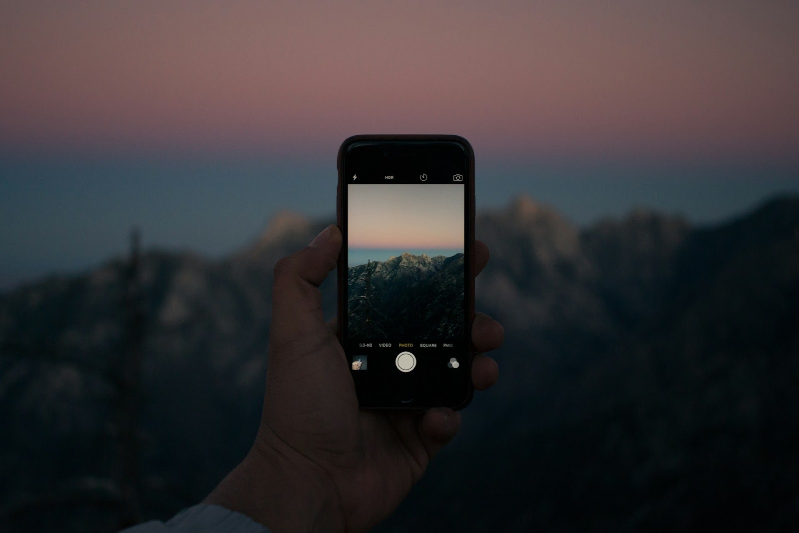 Someone taking a low-light photo of some mountains on an iPhone