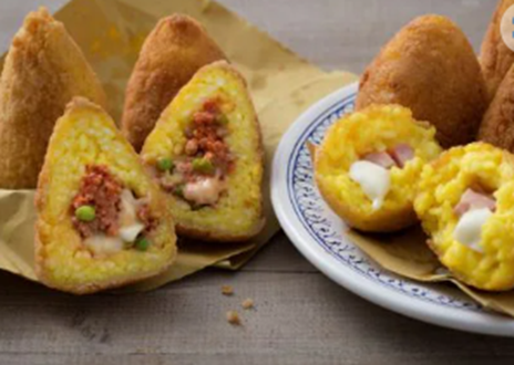 Arancini: Fried rice balls filled with ragù, mozzarella, and peas, originating from Sicily.