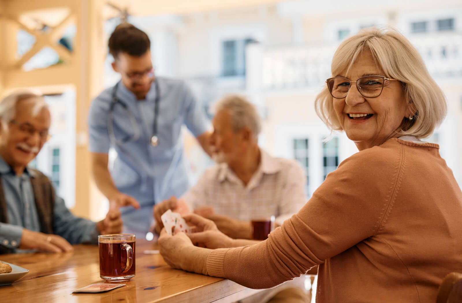 Group of seniors sitting around a table drinking coffee and playing cards.