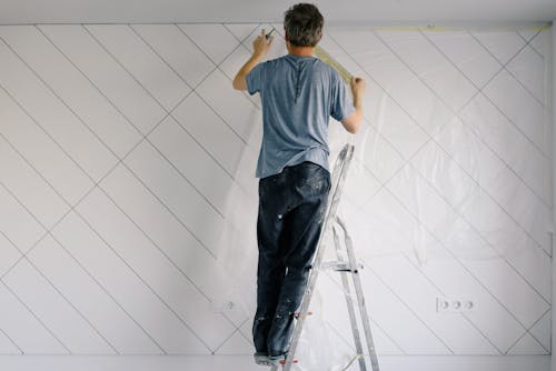 Free Faceless house painter undercoating wall in bright room Stock Photo