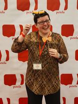 Image of Sarah Wilt, a young teacher, at the PCTELA selfie station, embracing wonder with a small hat and bow tie prop