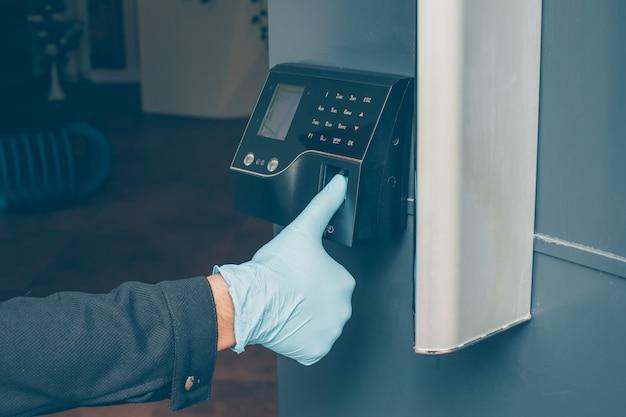 a man getting intercom to read his fingerprint to open the door with gloves on.  