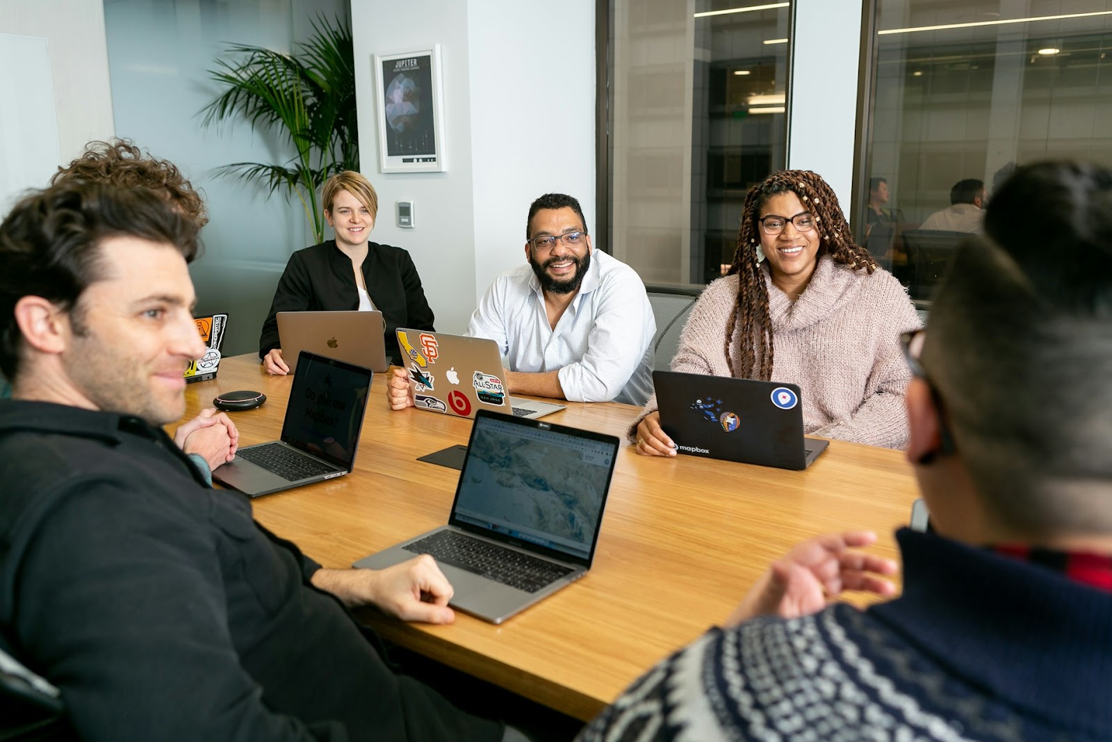 A team of people working together, sitting around a table with laptops, collaborating on a project.