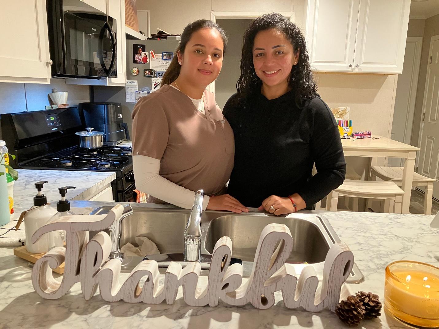 Two women standing in a kitchen

Description automatically generated