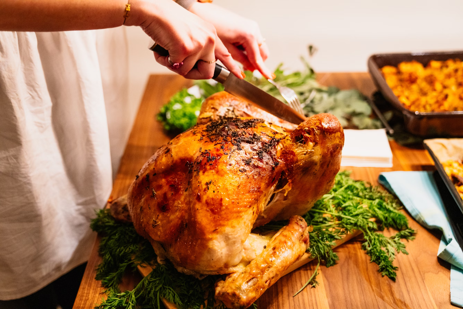 A person cutting slice of roasted chicken during Thanksgiving.