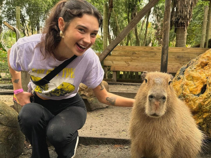 A woman poses happily while sitting next to a capybara at Wild Florida's Gator Park