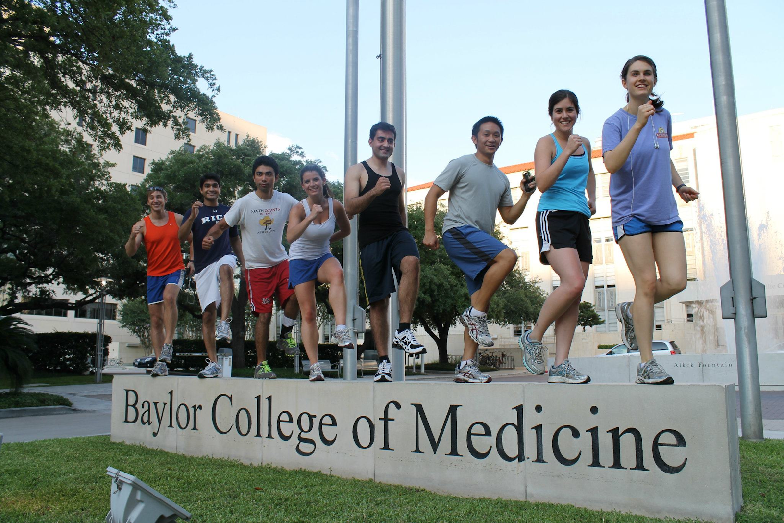A group of medical students standing at the stone signage