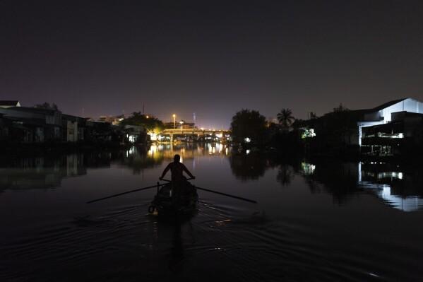 Nguyen Thi Thuy, a vendor selling steamed buns, navigates her boat through a river to reach the floating market before sunrise in Can Tho, Vietnam, Wednesday, Jan. 17, 2024. (AP Photo/Jae C. Hong)