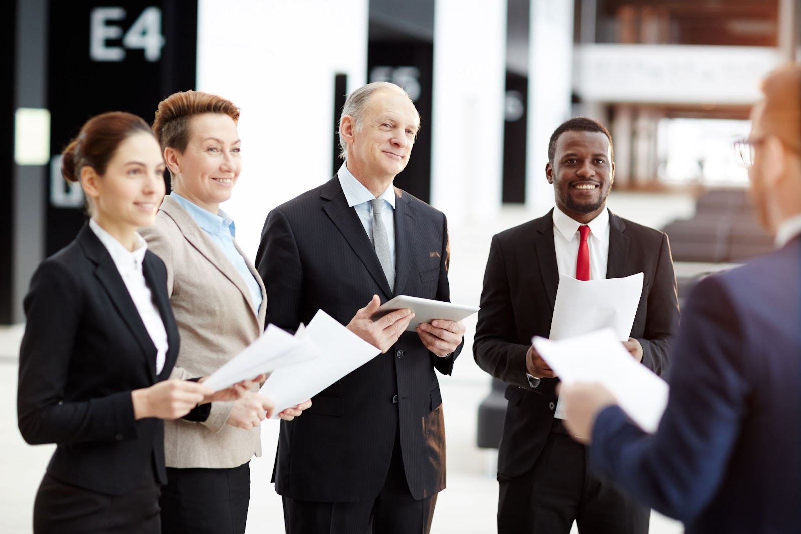 People in suits holding pieces of paper. 