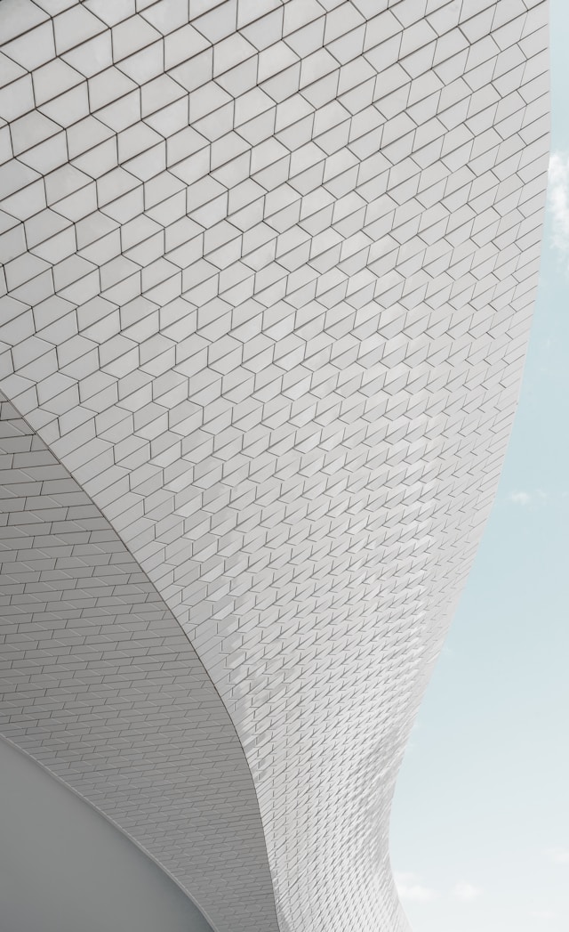 A grey patterned curved facade designed using BIM with a clear sky background