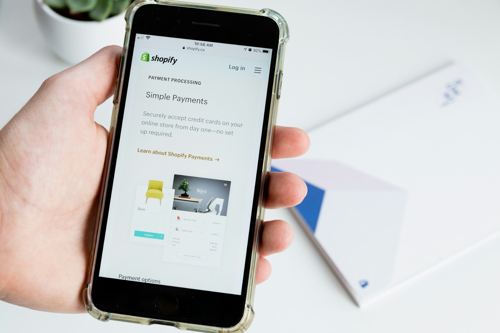 A person holding a smart phone with the Shopify Store showed from a phone