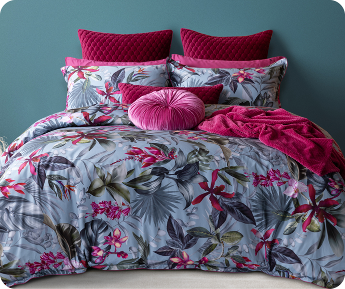 Our Botanical Sulani Duvet Cover shown styled on a bed with fuchsia pink accessories against a teal blue wall.