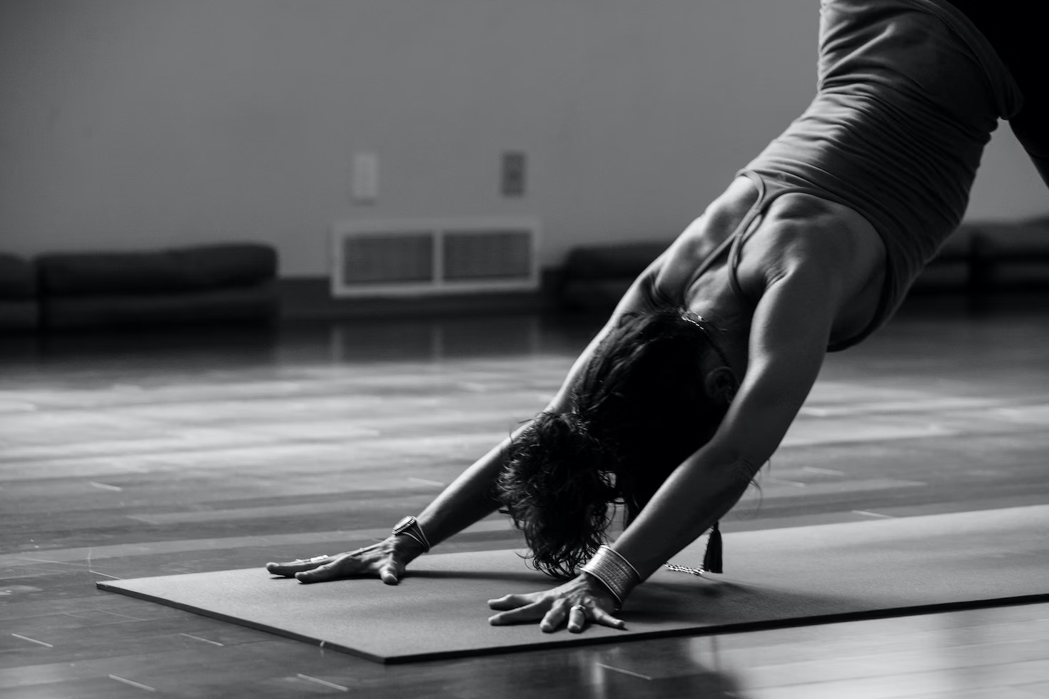 Woman in Black Tank Top Doing a Downward Dog Pose