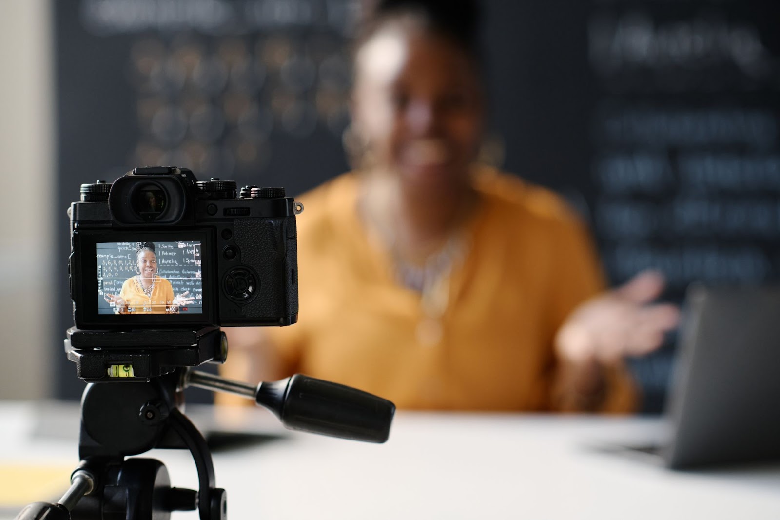 An online school teacher sits in front of a camera recording a future lesson
