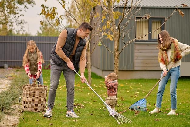 Man and woman with rake girl near basket in garden