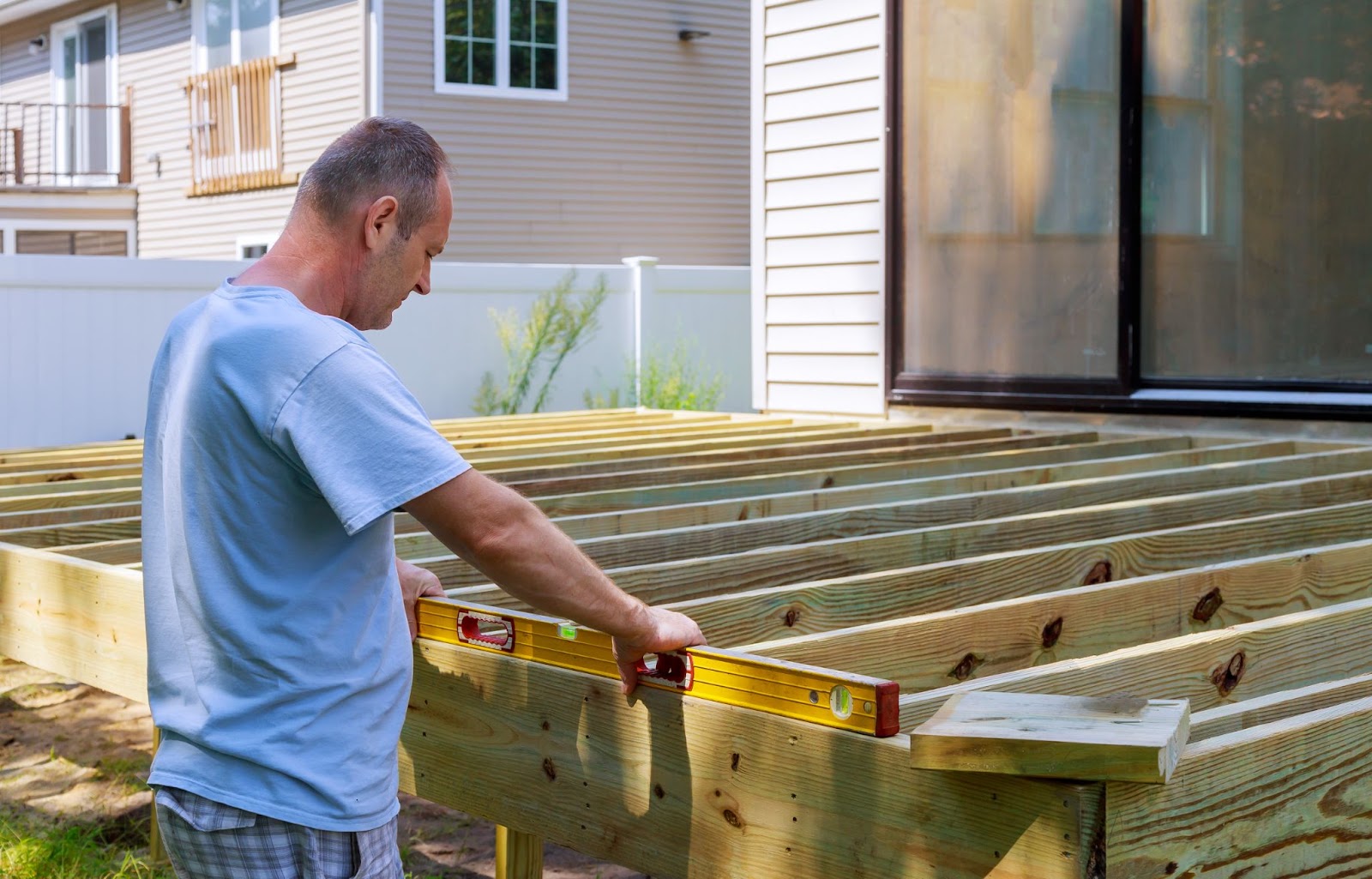 Man using a level for ground deck framing. 