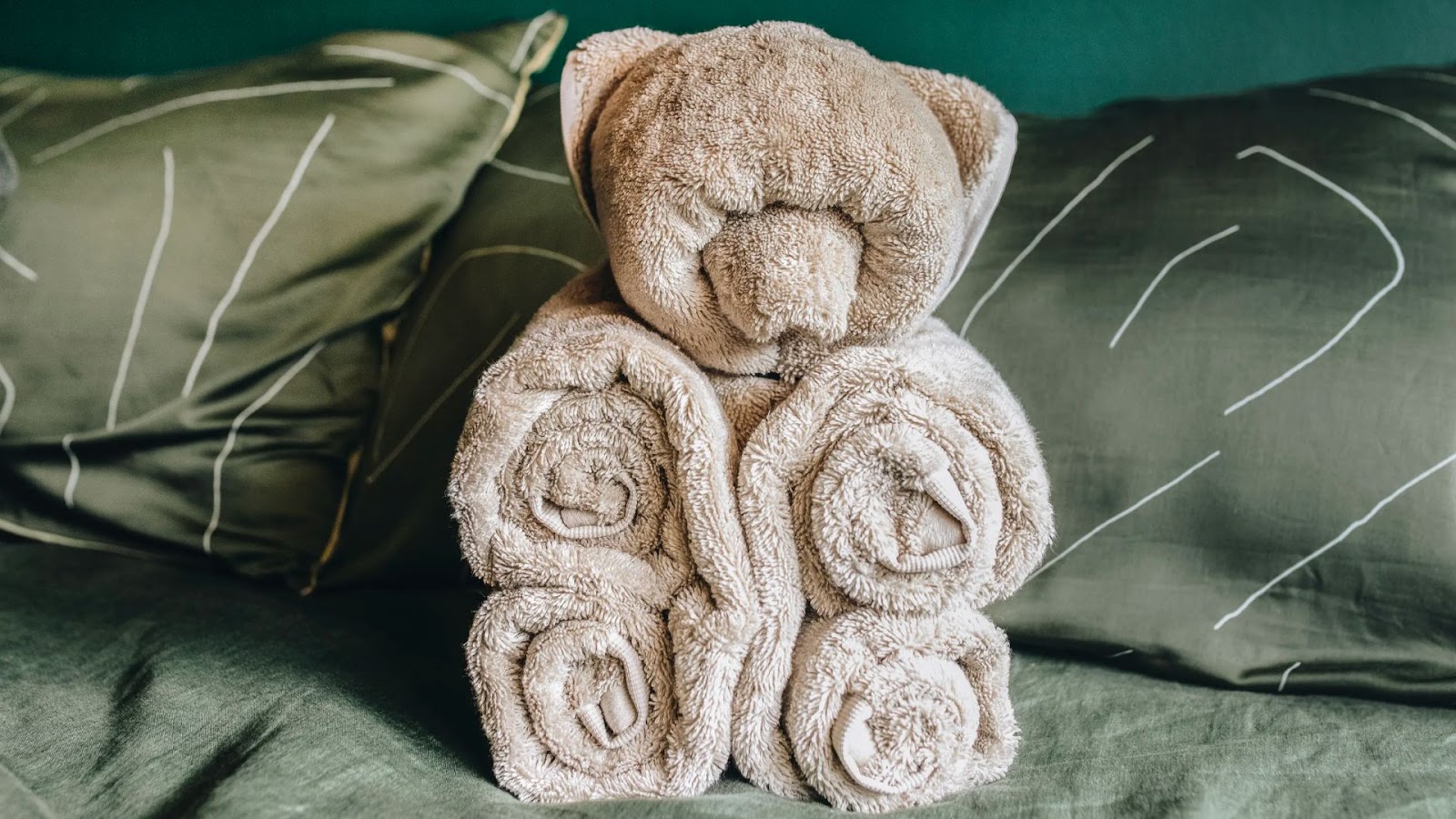 bear shaped animal folded towel sitting on a bed