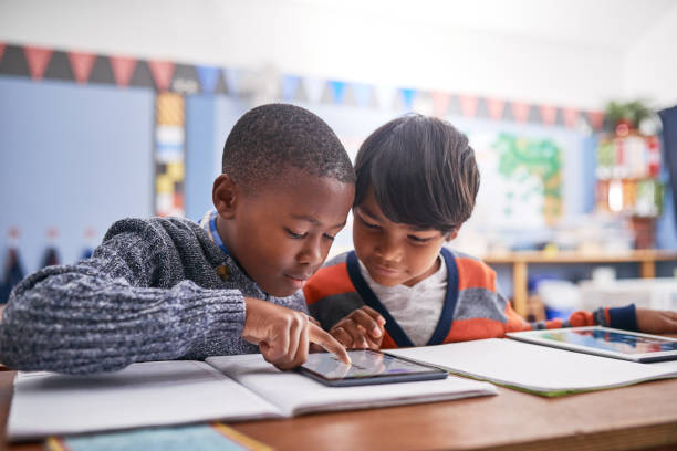 A child and a child looking at a tablet

Description automatically generated