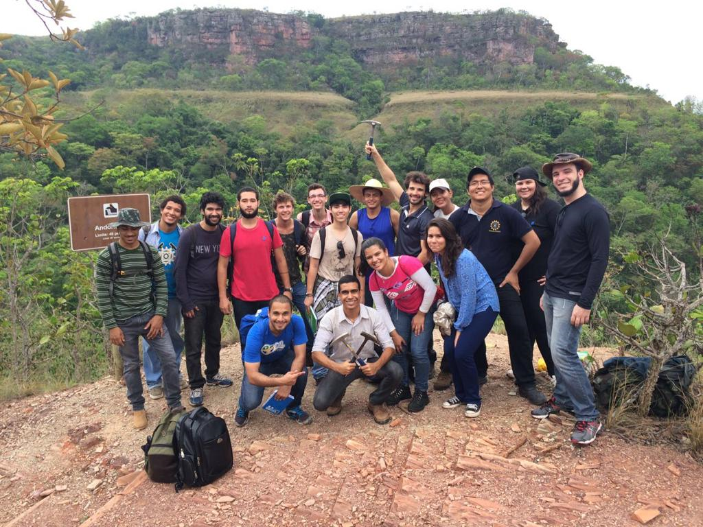 Grupo de pessoas na grama posando para foto com montanha ao fundo

Descrição gerada automaticamente