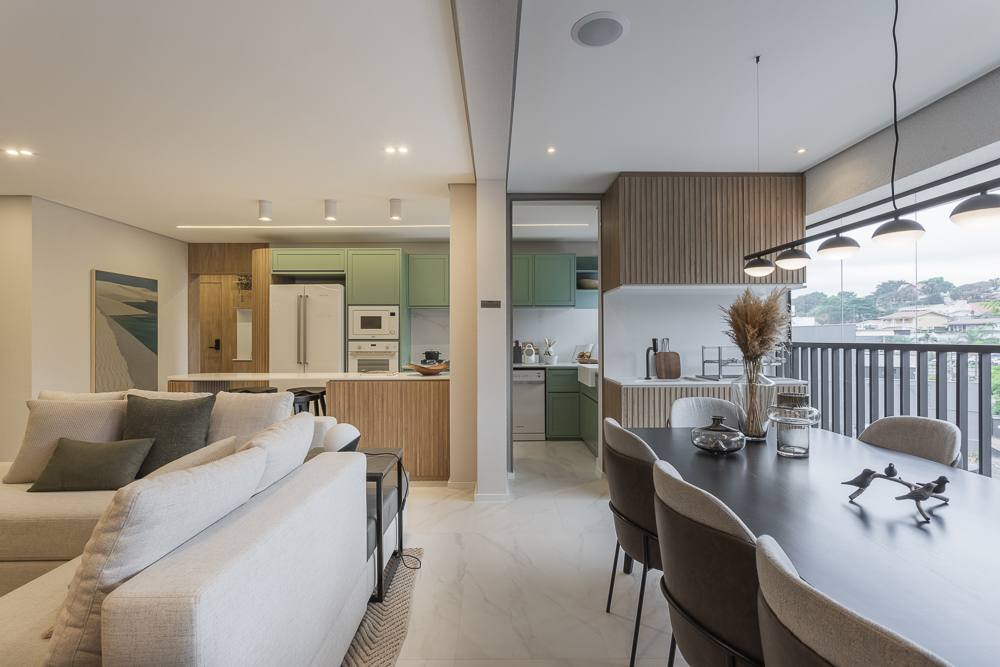 Foto de sala e cozinha conjugados nesse apartamento com cores claras e móveis de madeira.