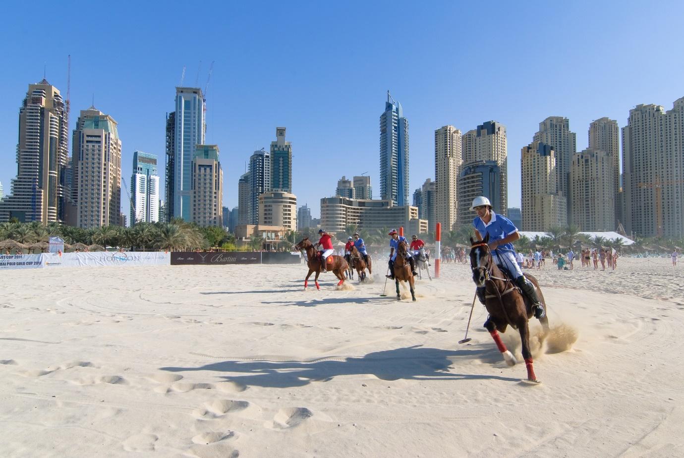 A group of people playing polo on a beach

Description automatically generated