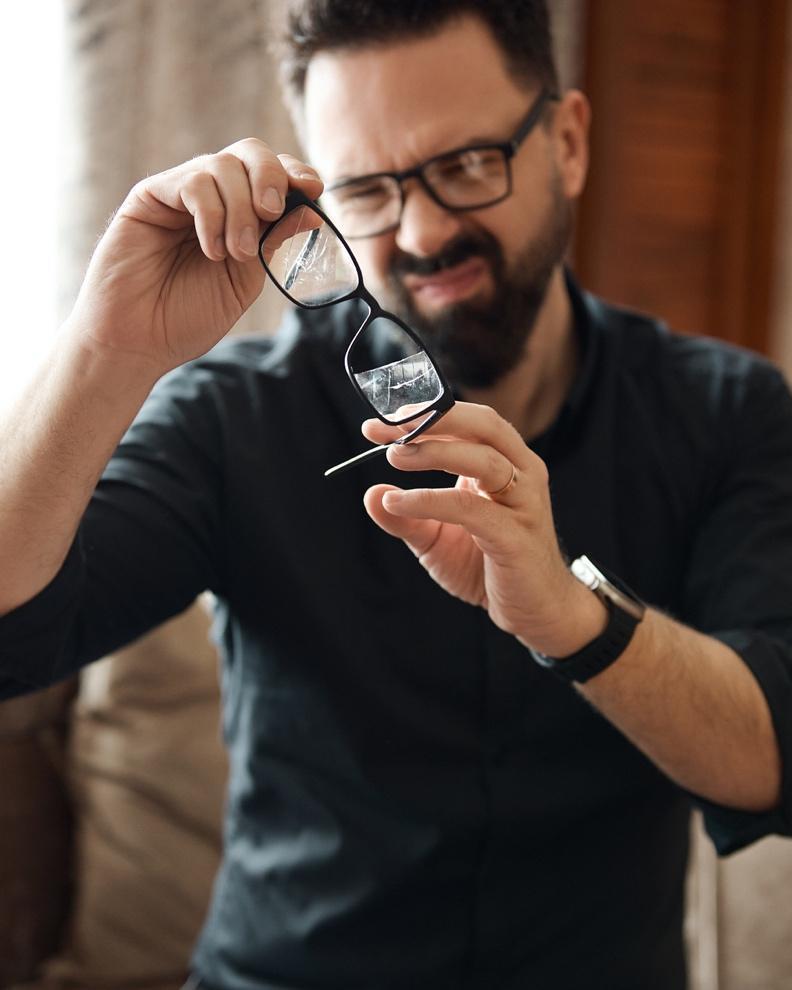 A person holding up his glasses

Description automatically generated