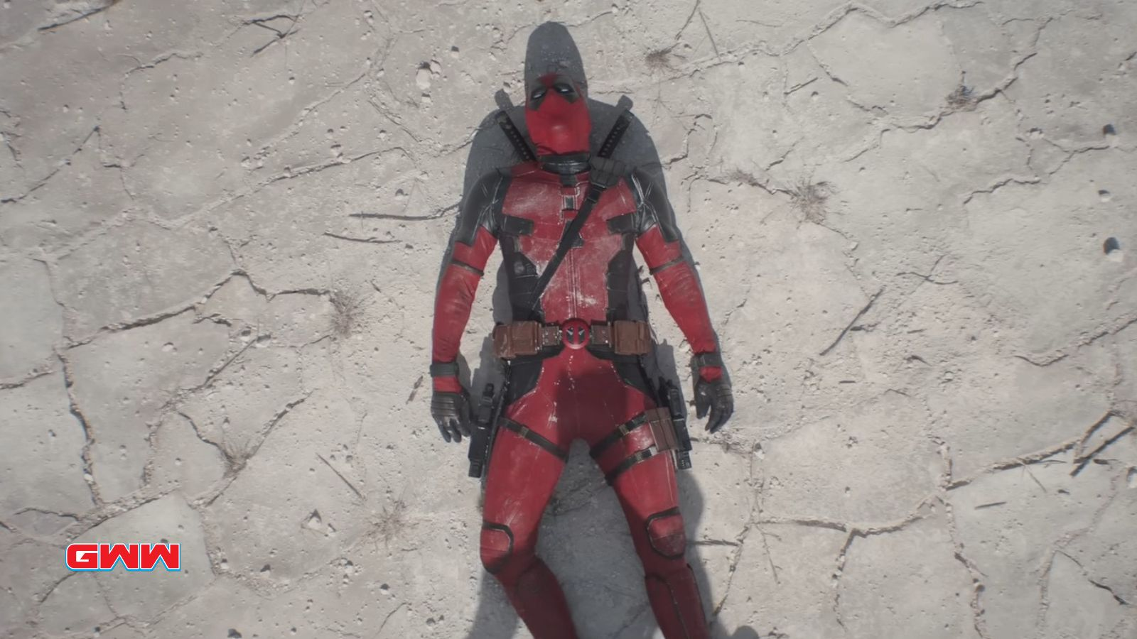 Person in red and black suit lying on cracked ground.