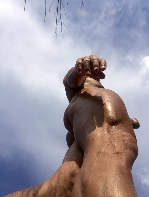 Matthew Figata close up of his muscled claves with a selfie from the ground revealing the cut tip of his penis head
