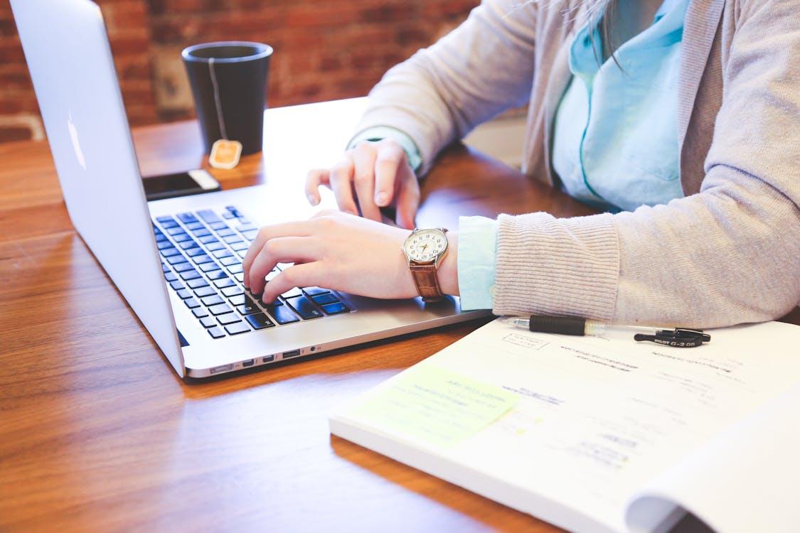 Free Person Using Macbook on Table Stock Photo