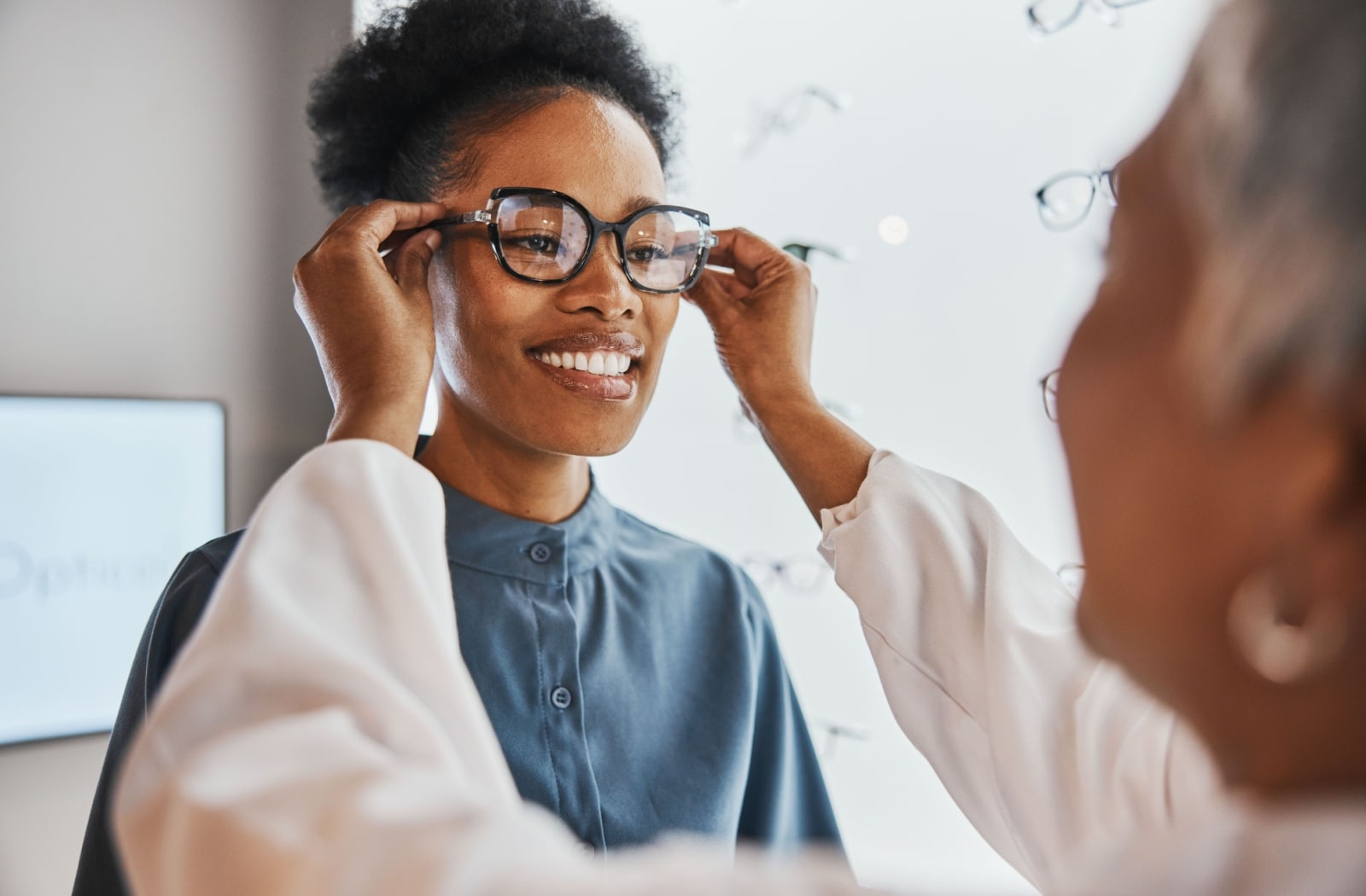 An optometrist adjusts a female patient's glasses on her head