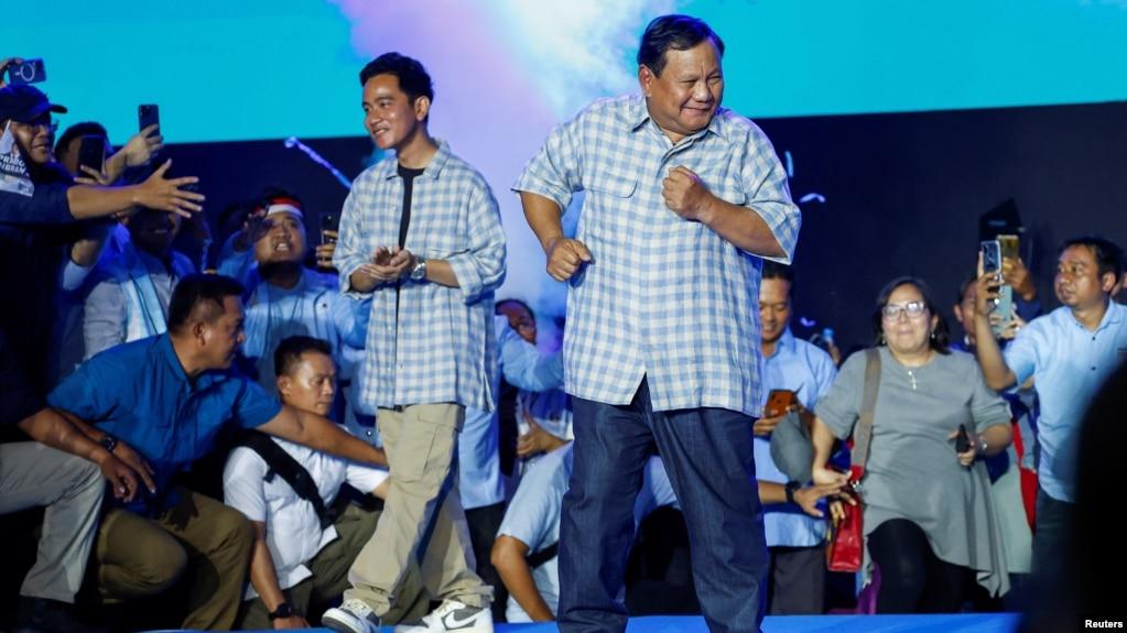 Bộ trưởng Quốc phòng Indonesia và ứng cử viên Tổng thống hàng đầu Prabowo Subianto (phải), cùng với người tranh cử Gibran Rakabuming Raka, con trai Tổng thống Joko Widodo, khiêu vũ sau khi phát biểu tại một sự kiện công bố kết quả đếm nhanh ở Jakarta, Indonesia, ngày 14/2/2024.