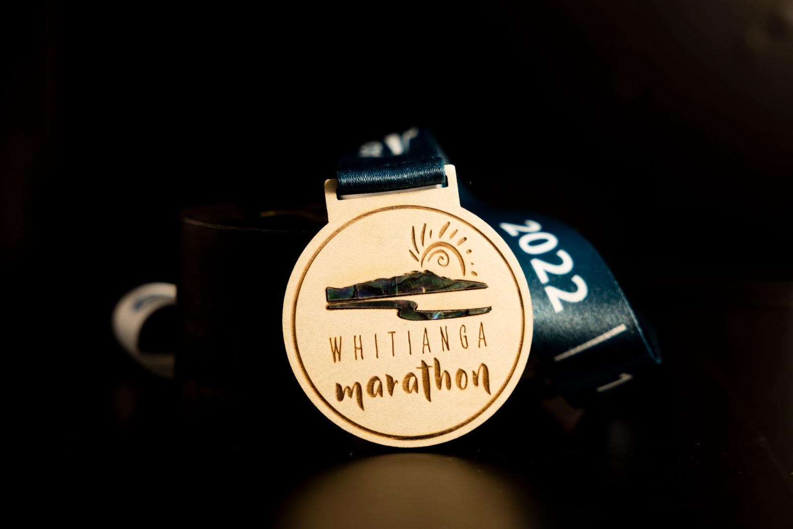 A custom wooden medal with seashell, made for Whitianga Marathon.